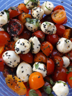 Una foto de Ensalada de tomatitos variados y boconccini con jamón crujiente y sésamo negro