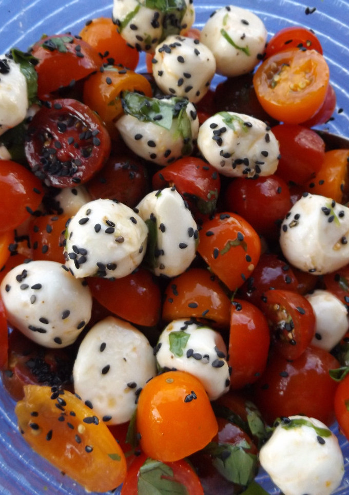 Una foto de Ensalada de tomatitos variados y boconccini con jamón crujiente y sésamo negro