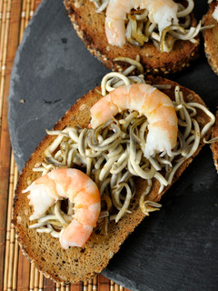 Una foto de Tostas de pan de centeno con gulas y langostinos