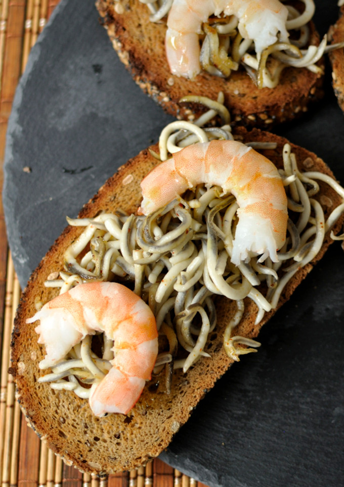 Una foto de Tostas de pan de centeno con gulas y langostinos