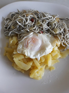 Una foto de Huevo frito con patatas y gulas al ajillo