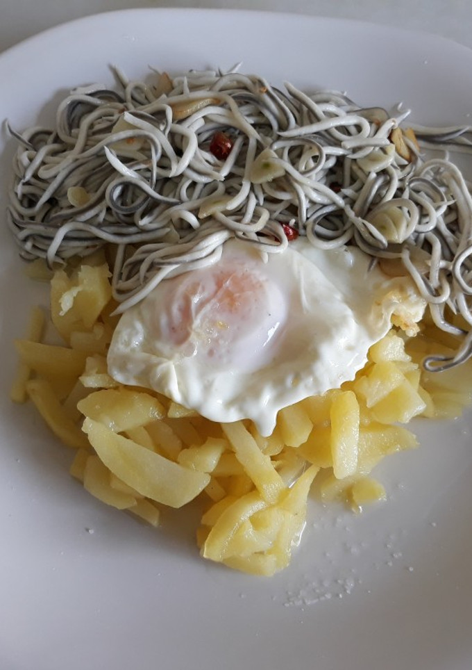 Una foto de Huevo frito con patatas y gulas al ajillo