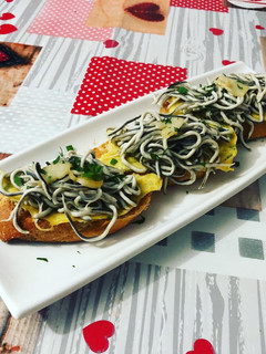 Una foto de Tostadas de gula al ajillo con tortilla de perejil picado