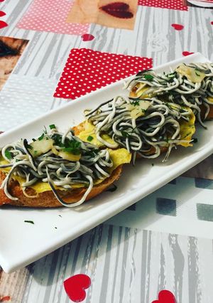 Una foto de Tostadas de gula al ajillo con tortilla de perejil picado