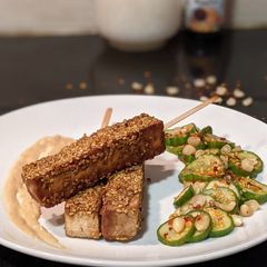 A picture of Tofu Satay with creamy peanut sauce and tangy cucumber salad.