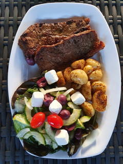 A picture of Sirloin Steaks with fried baby potatoes & a greek salad.