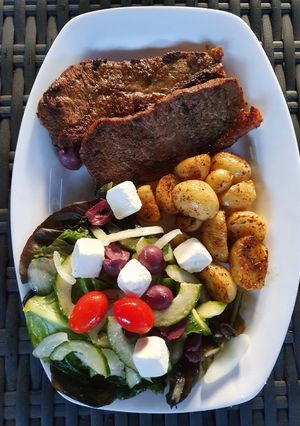A picture of Sirloin Steaks with fried baby potatoes & a greek salad.