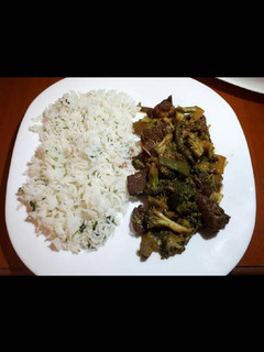 A picture of Meat with broccoli served with white rice.
