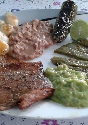 Una foto de Carne asada a la BBQ con guarniciones "Estilo enojona"