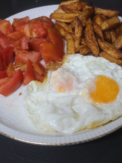 Una foto de Huevos fritos con patatas y tomate crudo