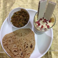 A picture of Mushroom masala with paratha and layered fruit custard.