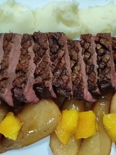 Una foto de Magret de pato con puré de patata acompañado de peras y dados de mango agridulces