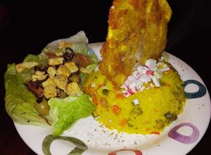 Una foto de Arroz con camarones y palmitos de cangrejo, acompañado de patacón pisado y ensalada