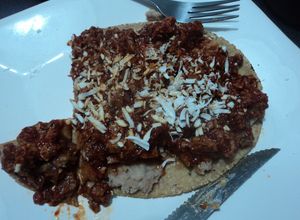 Una foto de Garnacha asada con chicharrón en salsa de chile cascabel y frijolitos con hierbas de olor