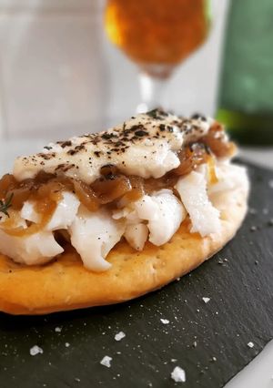 Una foto de Coca de bacalao confitado, cebolla caramelizada y salsa cabrales