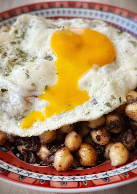 Una foto de Garbanzos salteados con morcilla y huevo frito