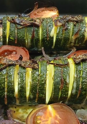 Una foto de Calabacines Hasselback con Panceta y Gouda sobre Lecho de Tomate y Cebolla