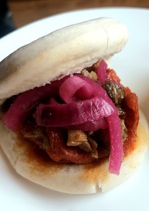 Una foto de Pan bao relleno de sobrasada picante, carrillera guisada y cebolla morada encurtida