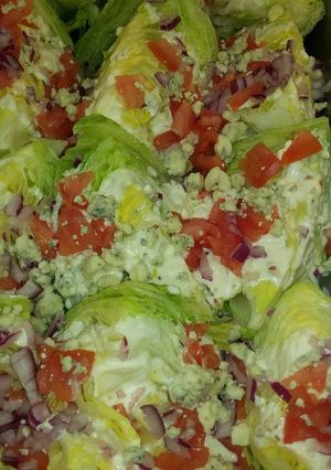 Una foto de Ensalada de lechuga con queso azul, cebolla morada y tomate