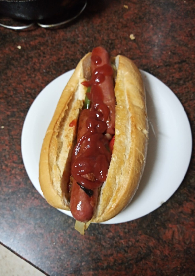Una foto de Perrito caliente isleño (salteado de cebolla y pimiento) y ketchup