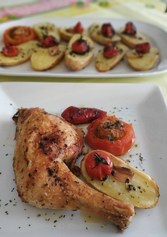 Una foto de Pollo con patatas, tomates y pimiento al ajo y perejil