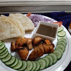 A picture of Chicken tikka with chutney and paratha.