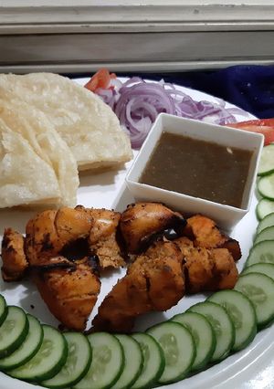 A picture of Chicken tikka with chutney and paratha.