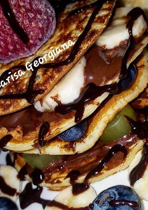 O poză a rețetei Pancakes cu nutella și fructe.