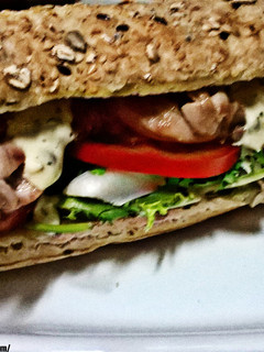 Una foto de Bocadillo de contramuslo de pollo, con vegetales, y salsa tártara, en pan rústico de cereales