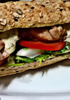Una foto de Bocadillo de contramuslo de pollo, con vegetales, y salsa tártara, en pan rústico de cereales