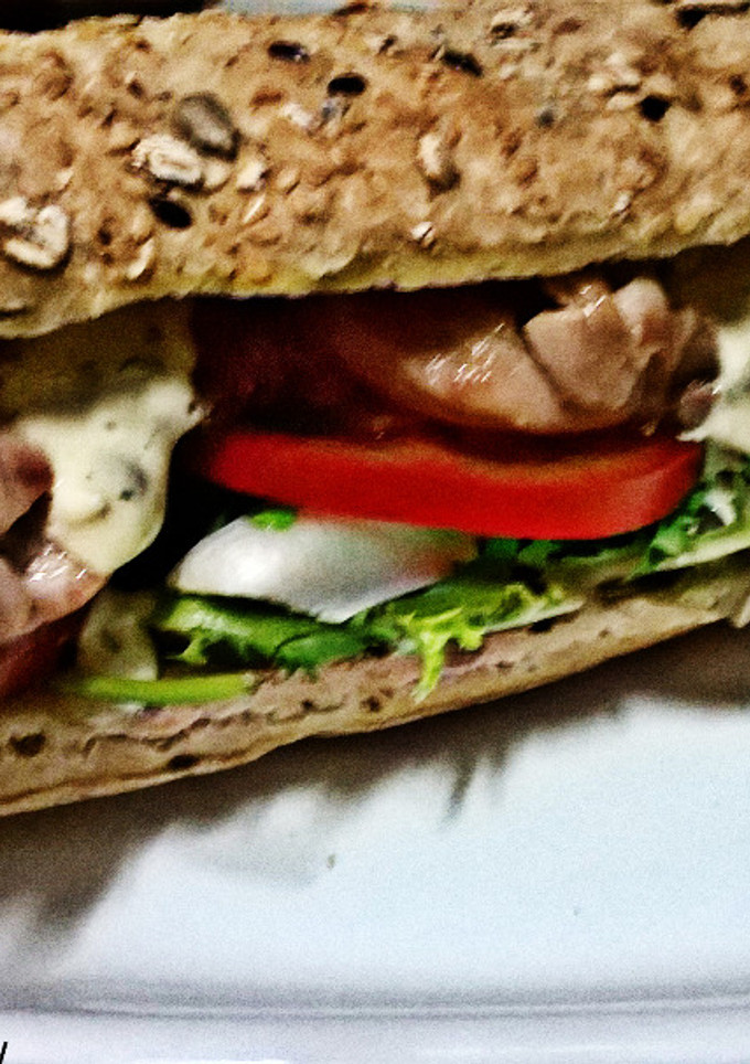 Una foto de Bocadillo de contramuslo de pollo, con vegetales, y salsa tártara, en pan rústico de cereales