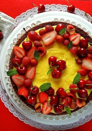 Foto di Torta al cacao con crema pasticcera fragole e ciliegie