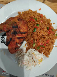 A picture of Jollof rice with coleslaw and fried chicken.