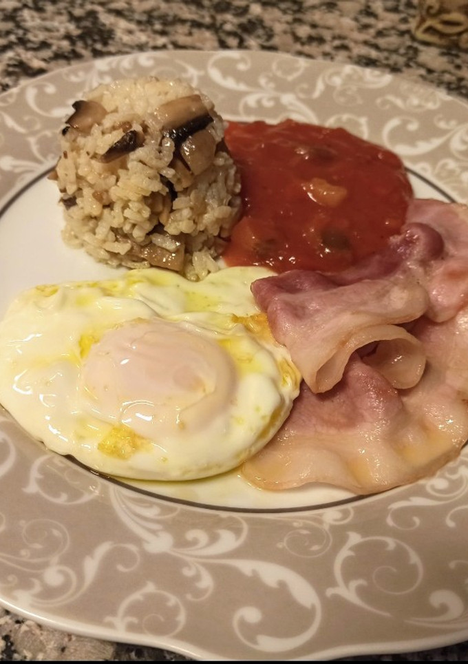 Una foto de Huevo frito con bacon, arroz y tomate con hortalizas