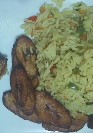 A picture of Fried rice with fried plantain and fried fish.