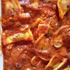 A picture of Ravioli with tomato and basil sauce.