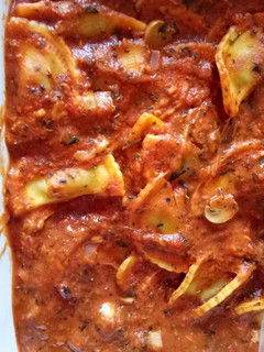 A picture of Ravioli with tomato and basil sauce.