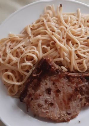 Una foto de Chuleta de Cerdo con Tallarines y acompañada de Tomate al Comino