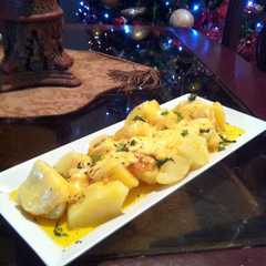 Una foto de Papas a la mantequilla de ajo con queso gruyer derretido.