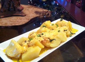 Una foto de Papas a la mantequilla de ajo con queso gruyer derretido.