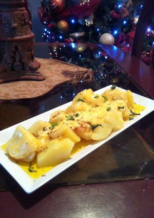 Una foto de Papas a la mantequilla de ajo con queso gruyer derretido.