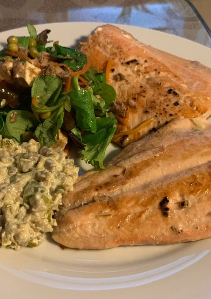 Una foto de Salmón con guarnición de ensalada y salsa de champiñones