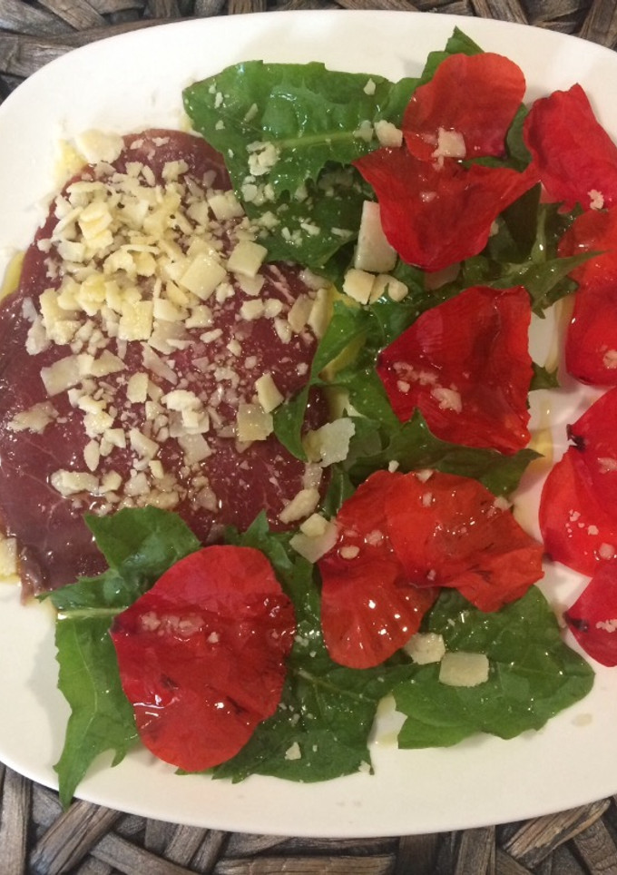 Una foto de Carpaccio con pétalos de amapola y diente de león