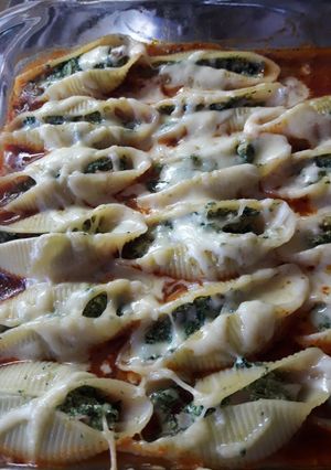 Una foto de Conchiglioni relleno de espinaca y ricota sobre salsa boloñesa