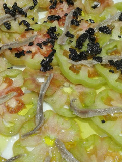 Una foto de Carpacio de tomate con anchoas y picada de aceitunas negras