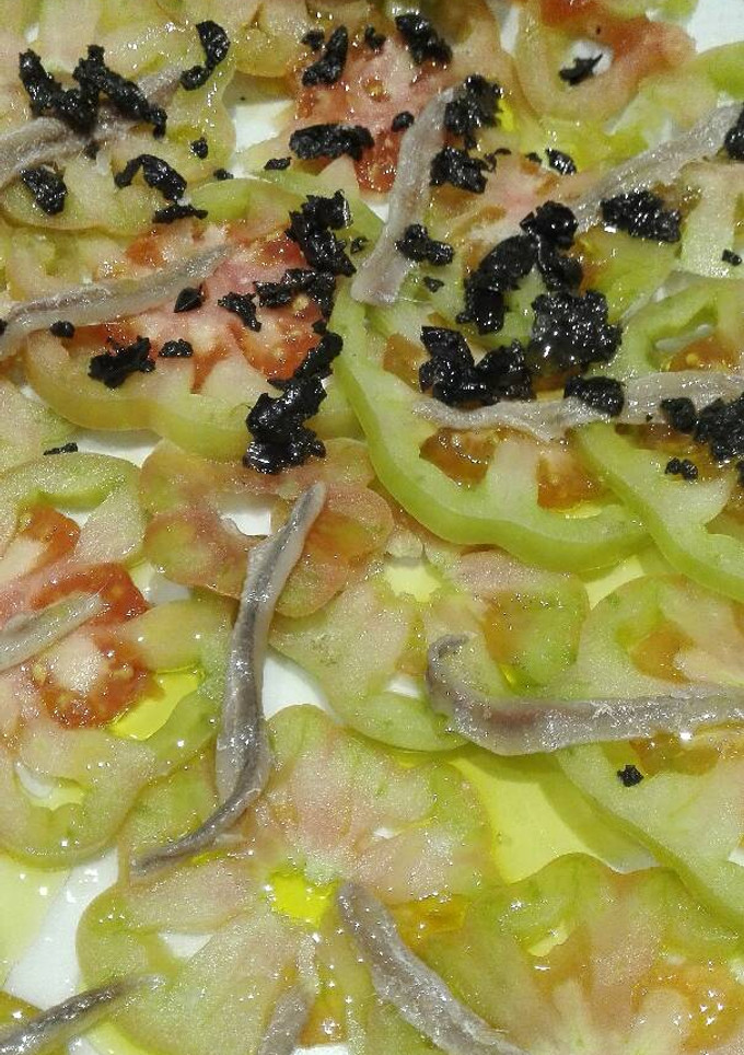 Una foto de Carpacio de tomate con anchoas y picada de aceitunas negras