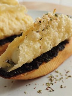 Una foto de Pincho de cono de parmesano relleno de brandada y olivada