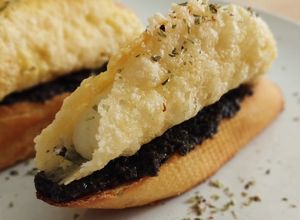 Una foto de Pincho de cono de parmesano relleno de brandada y olivada