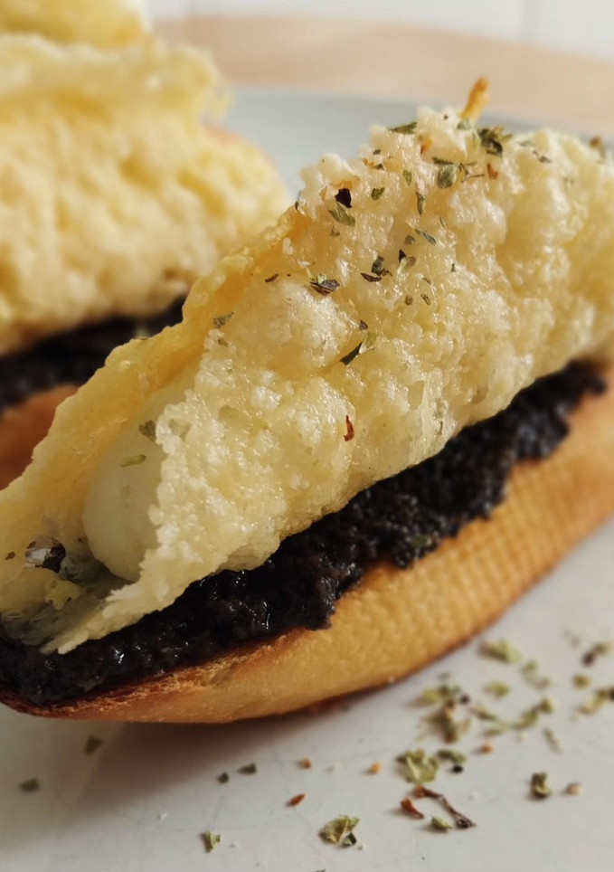 Una foto de Pincho de cono de parmesano relleno de brandada y olivada