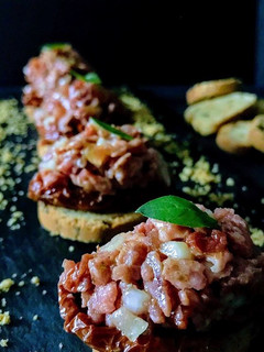 Una foto de Tartar de fuet con tomates secos en aove y polvo de morro tostado